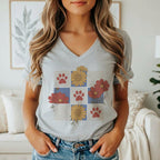 Gray t-shirt with a graphic of red paw prints and flowers on a grid.