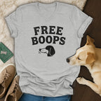 Gray t-shirt with "FREE BOOPS" text and dog illustration, near a dog.