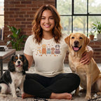Woman wearing a cream t-shirt with a cartoon dog print, sitting with three dogs.