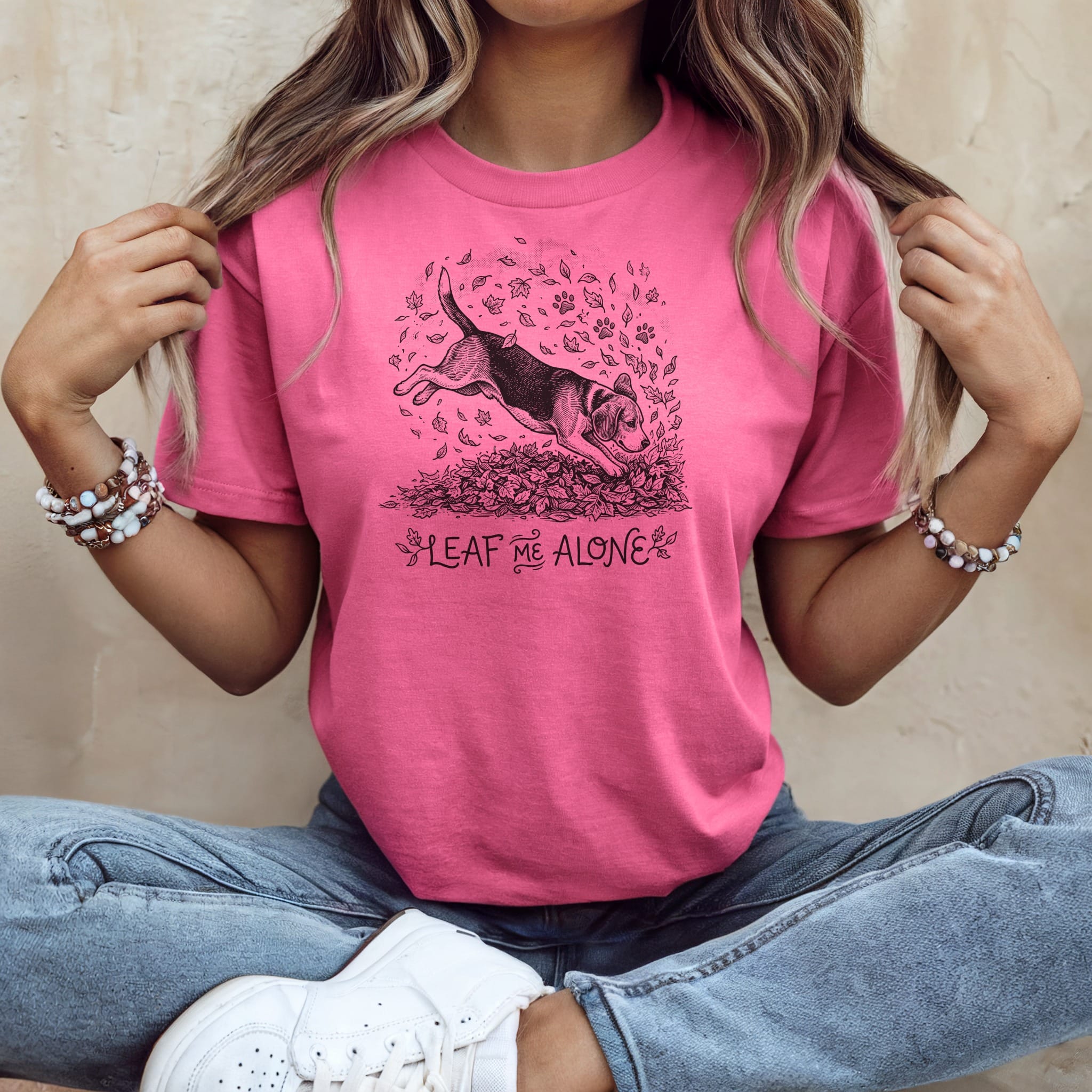T-shirt with beagle jumping through autumn leaves and text "Leaf Me Alone."