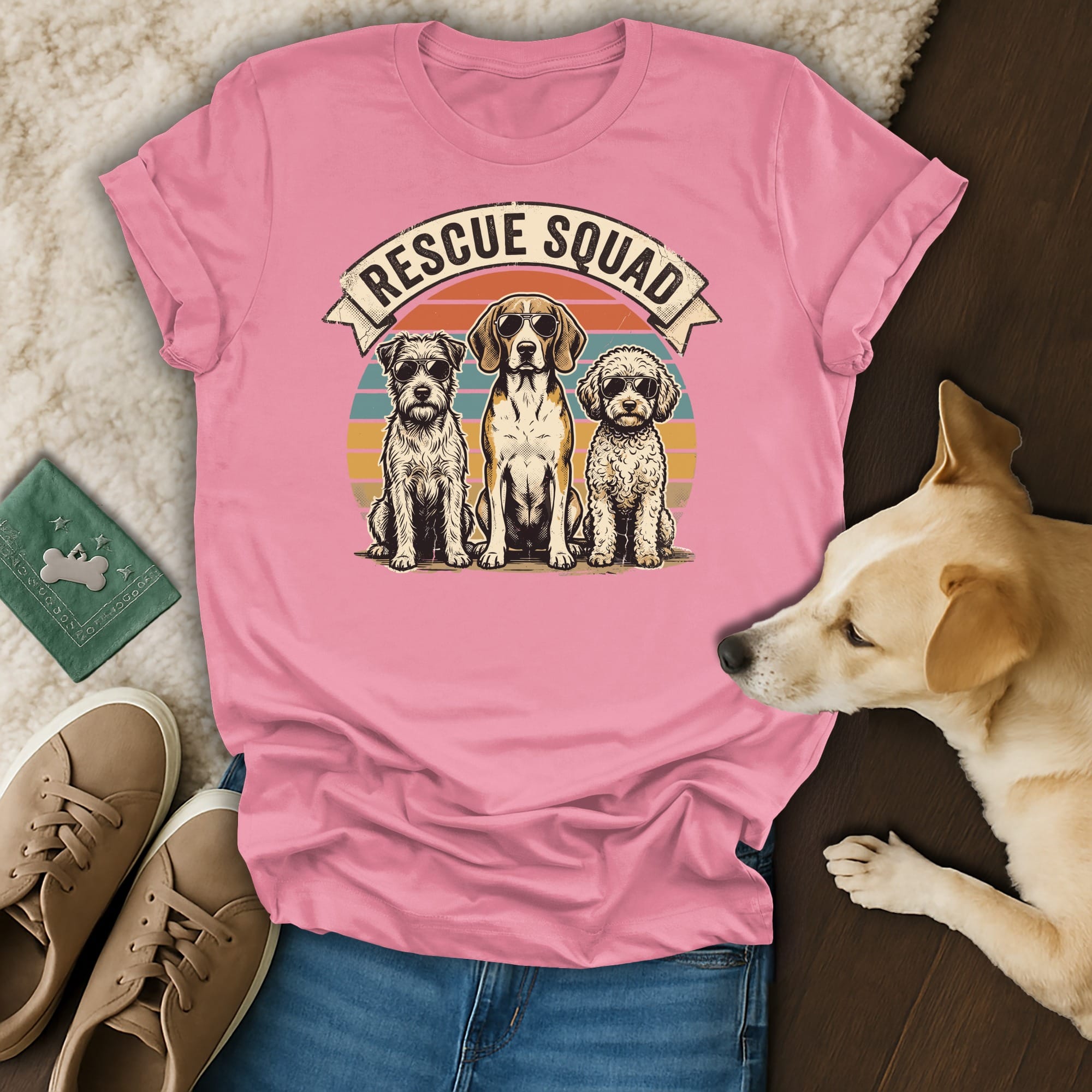 Three dogs wearing "Rescue Squad" banner sit on pink t-shirt.