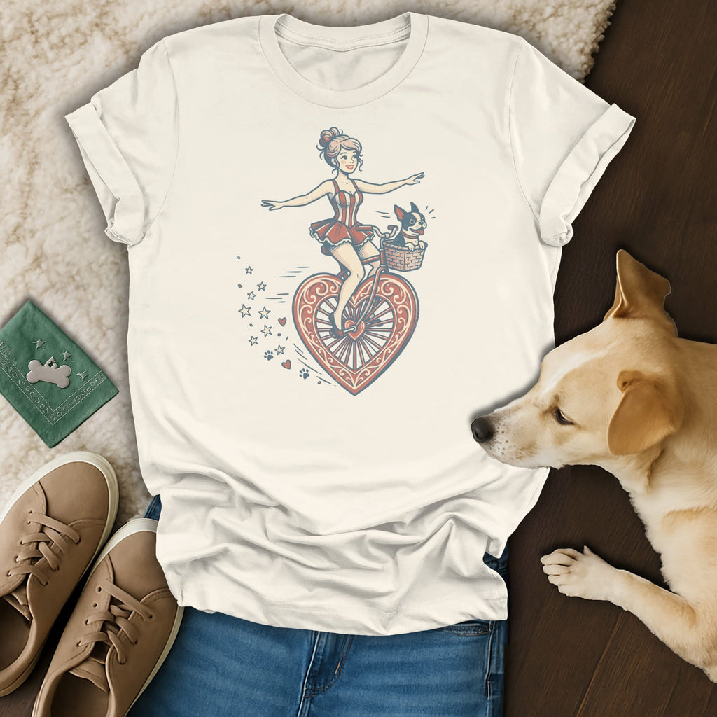 Graphic tee with cartoon of woman riding heart-shaped bicycle with a dog in basket.