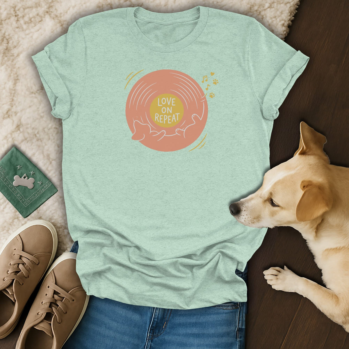 Mint green t-shirt featuring a vinyl record graphic with the text Love on Repeat, paired with jeans, sneakers, and a sleeping dog.