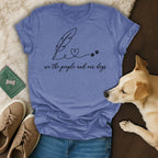 Blue t-shirt with feather, heart, and paw prints graphic and "we the people and our dogs" text.