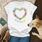 White t-shirt with colorful paw print heart, butterfly, and text.