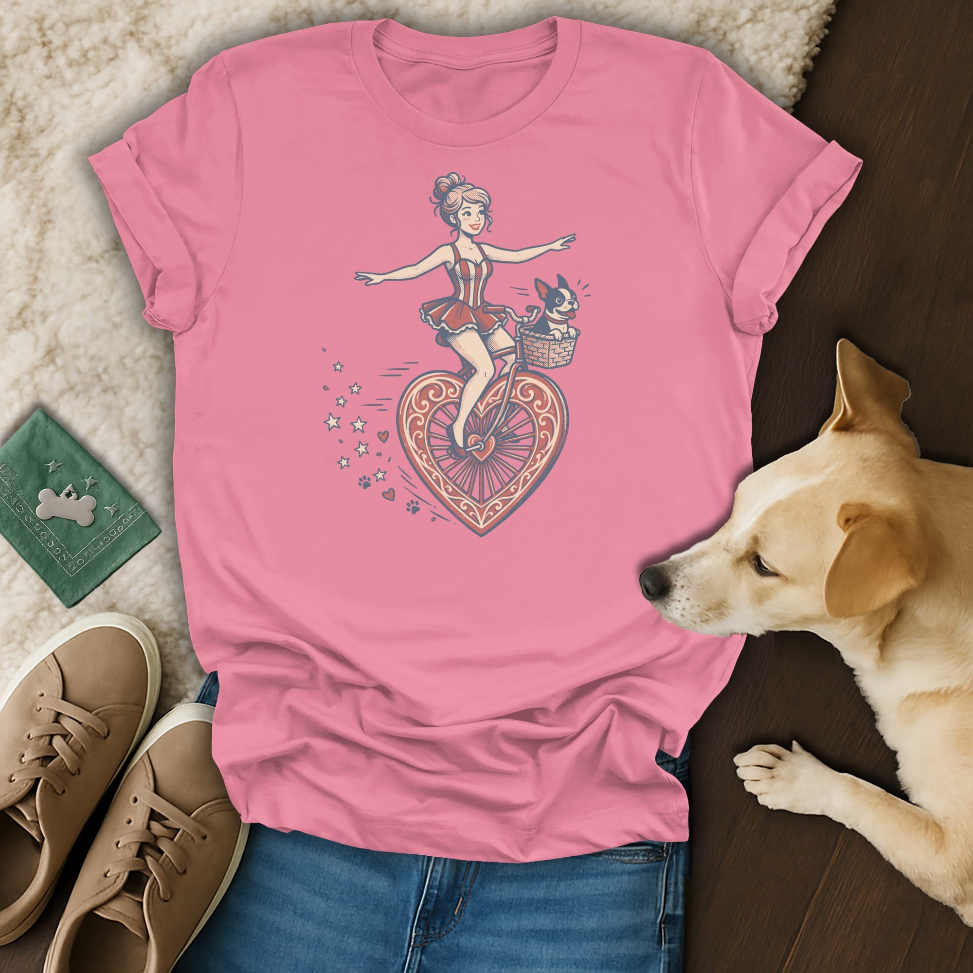 Pink t-shirt with a woman riding a heart-shaped bicycle with a dog in the basket.