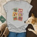 Gray crewneck t-shirt featuring a dog-themed postage stamp graphic, laid flat with jeans, shoes, and a dog.