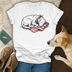 White t-shirt with a sleeping dog graphic on an American flag pillow.