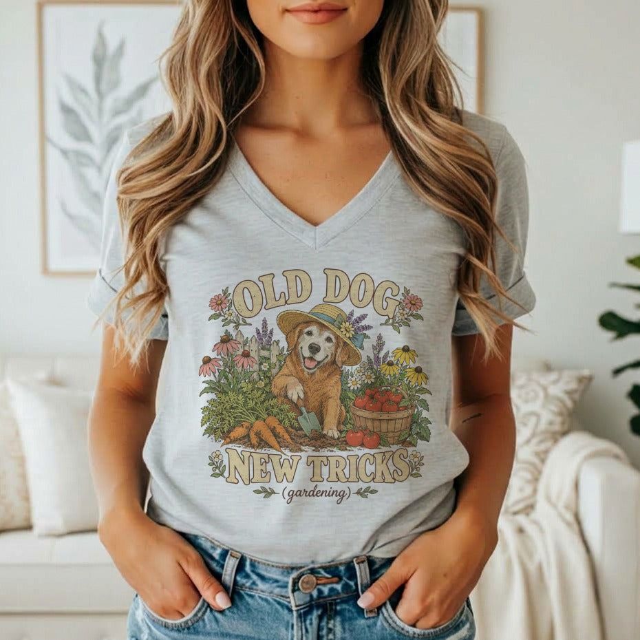 A woman wearing a gray V-neck t-shirt featuring a vintage gardening golden retriever graphic and text.