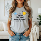 Grey t-shirt with "Chasing Sunshine because the dog won't poo in the rain" text.