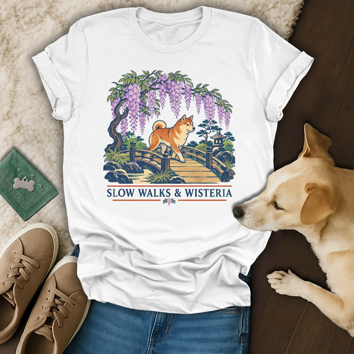 A white t-shirt featuring a Japanese-style graphic of a Shiba Inu crossing a bridge under wisteria, with the text SLOW WALKS & WISTERIA.