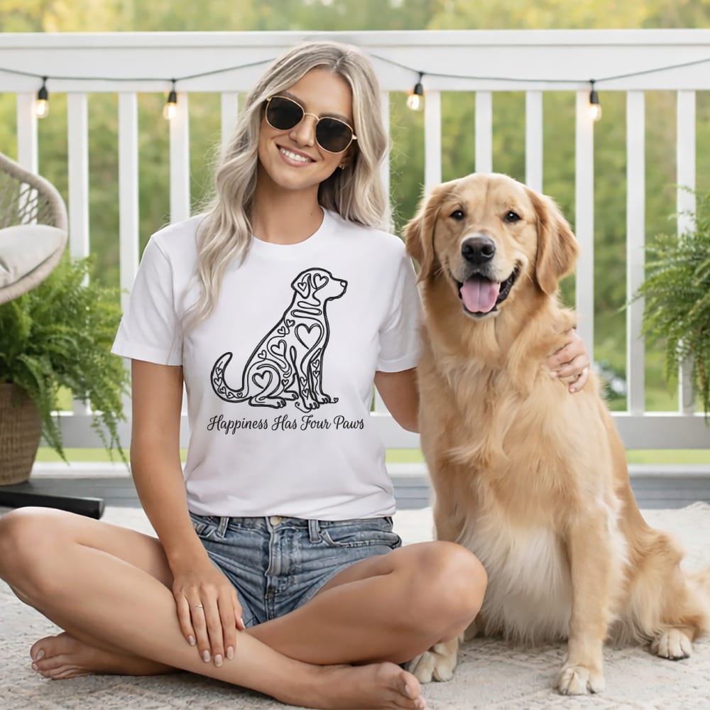 Woman in t-shirt with "Happiness Has Four Paws" design sits with golden retriever.