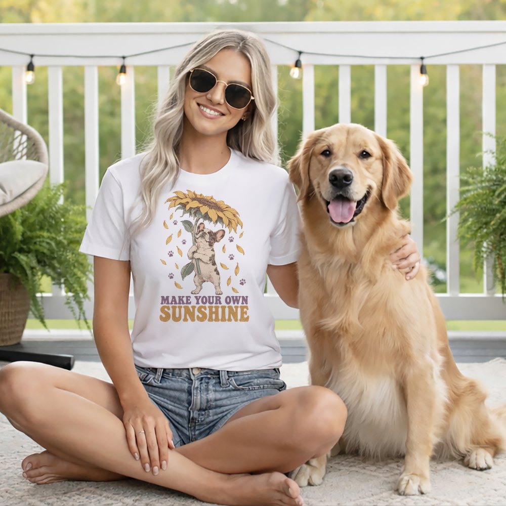 Blonde woman wearing a white t-shirt and sunglasses sitting cross-legged next to a golden retriever on a patio.