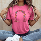A person wearing a pink t-shirt with a floral arch illustration featuring colored paw prints.