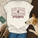 Cream t-shirt with "DOG PARK ATHLETICS PROFESSIONALLY TRAINED (BY MY DOG)" text.