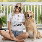 Woman with golden retriever wearing a white t-shirt with a dog graphic and "TAILWIND".
