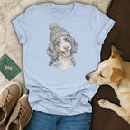 Light blue t-shirt with a drawing of a dog wearing a beanie.