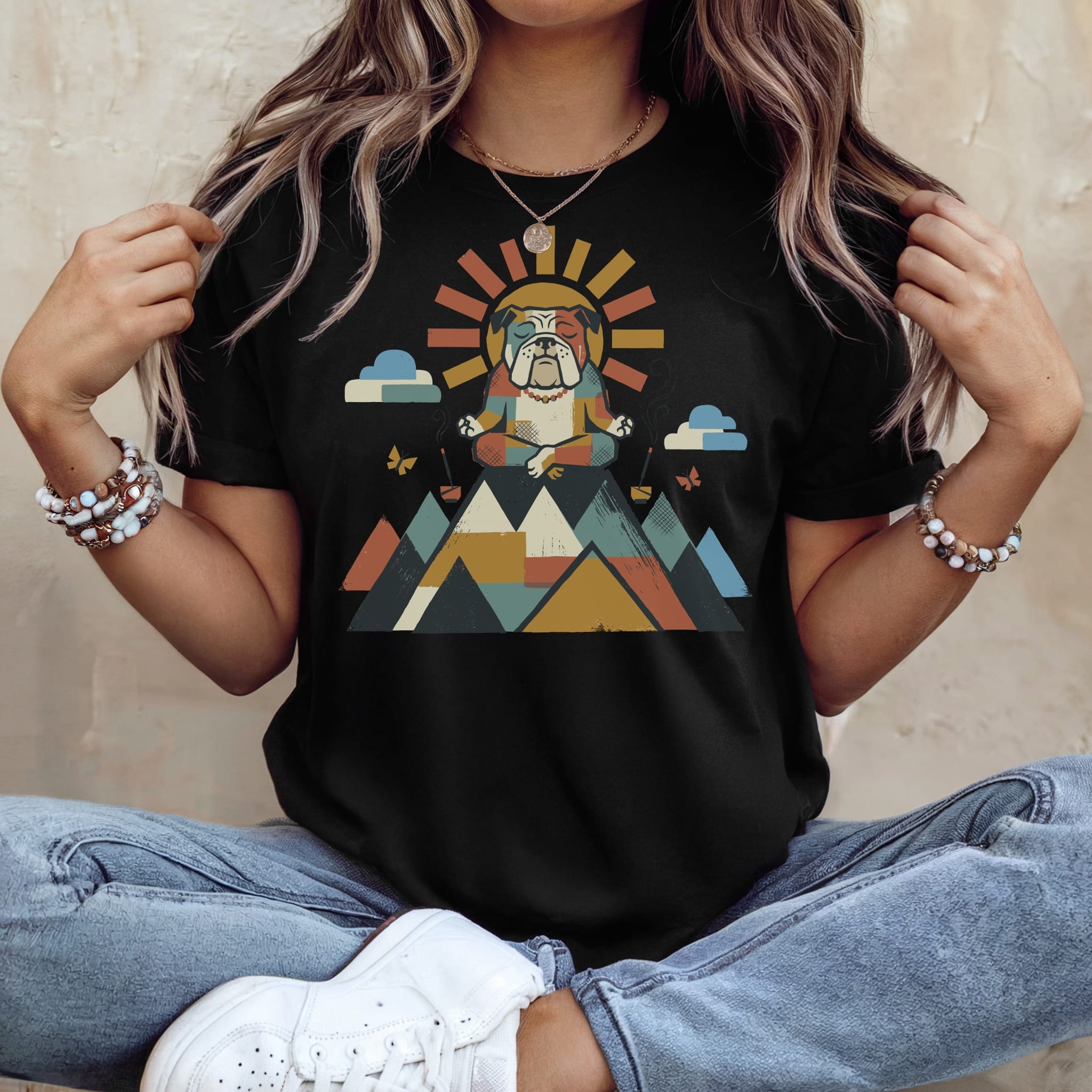 Bulldog meditating in colorful geometric mountains with sun and clouds graphic on black t-shirt.
