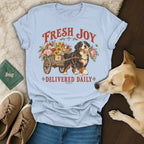 Light blue t-shirt featuring a Bernese Mountain Dog pulling a flower cart with text FRESH JOY DELIVERED DAILY.