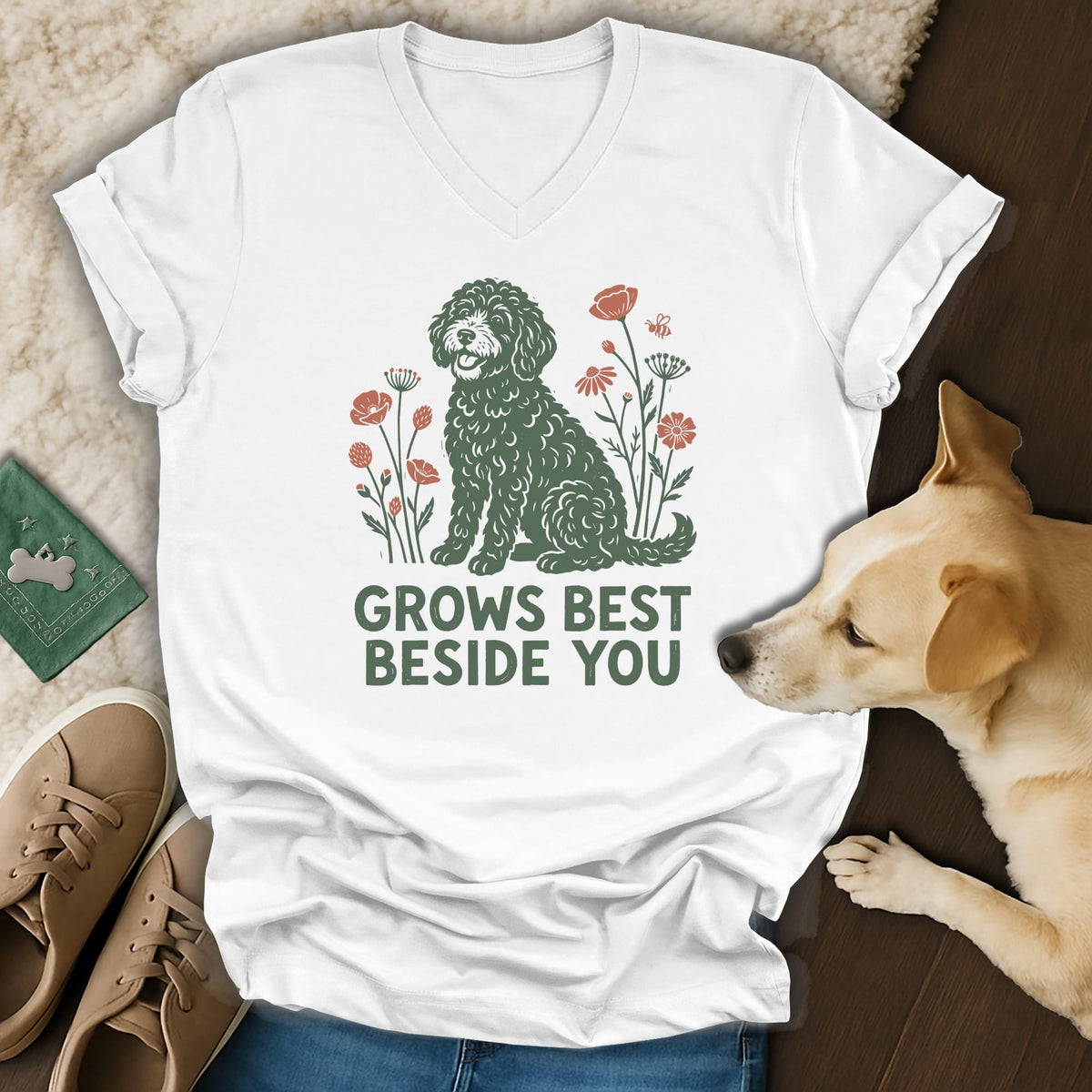 A white v-neck t-shirt featuring a green doodle dog graphic and the text GROWS BEST BESIDE YOU.