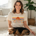 Woman wearing cream t-shirt with colorful dog illustrations and orange sun graphic.