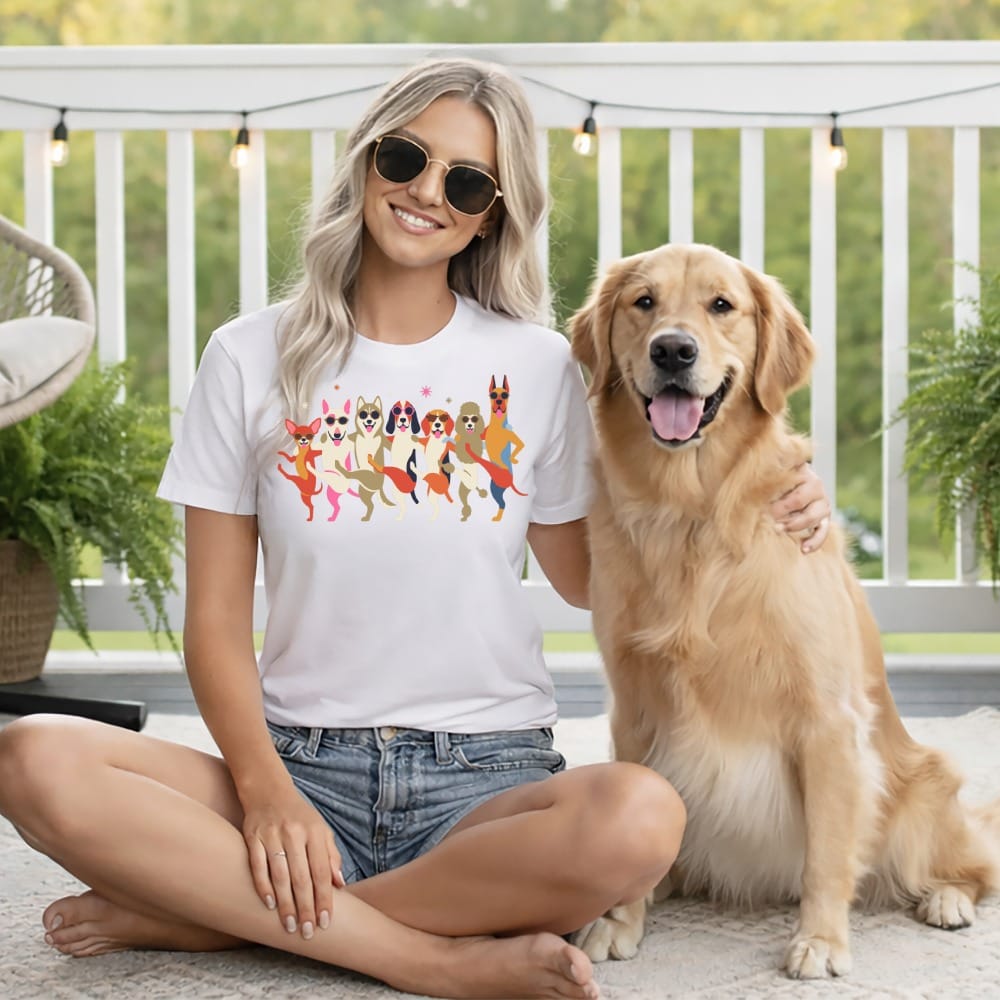 Woman wearing white t-shirt with colorful dog graphics sits next to golden retriever.