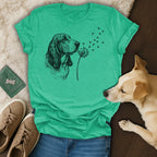 T-shirt with a sketched basset hound blowing dandelions that turn into paw prints.
