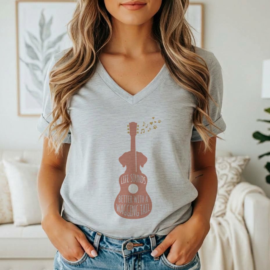 A person wearing a grey v-neck t-shirt featuring a pink guitar graphic with a dog silhouette and the text Life Sounds Better With A Wagging Tail.