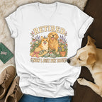 A white V-neck t-shirt with a graphic of a Corgi and Golden Retriever among flowers, and the text Retired Now I Just Pet Dogs.