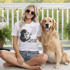Woman wearing a t-shirt with a dog and dandelion design, sitting with a golden retriever.