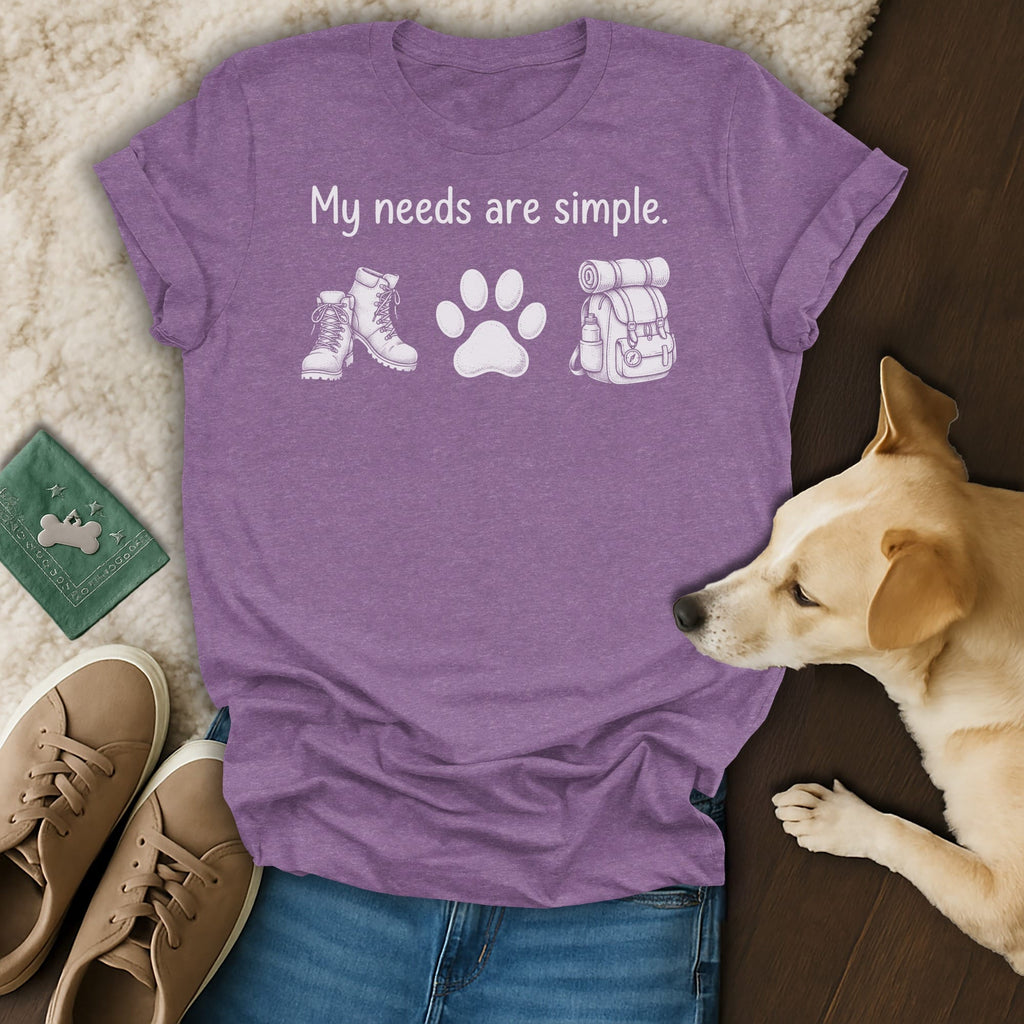 Purple t-shirt with "My needs are simple." and illustrations of boots, paw print, and backpack.
