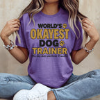 Purple t-shirt with "World's Okayest Dog Trainer" text in yellow and black.