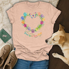 Peach t-shirt with a heart of colorful paw prints and a butterfly, reads "Grow Wild, Love Dogs."