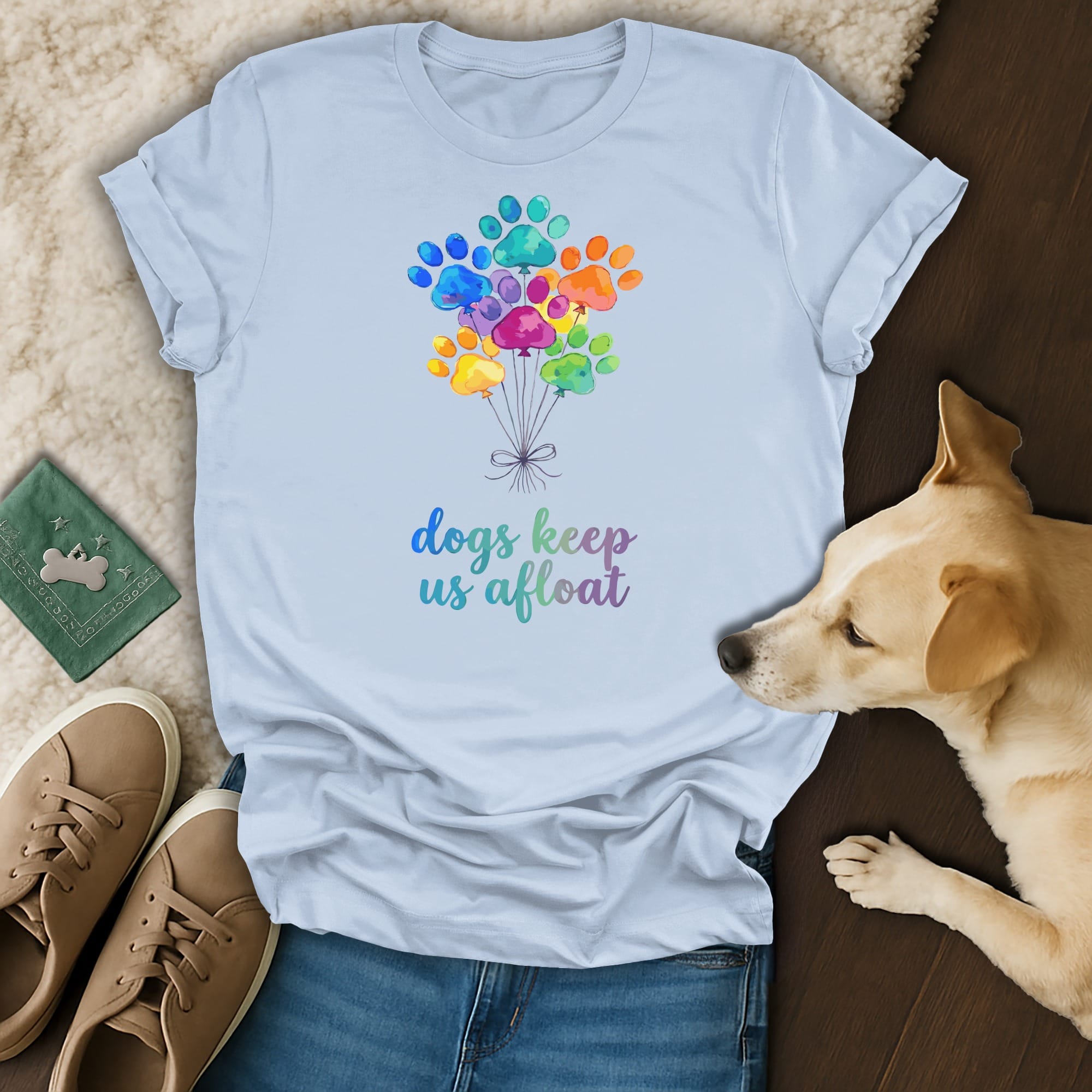 Light blue t-shirt with colorful paw print balloons and "dogs keep us afloat" text.