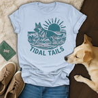 German Shepherd dog surfing on a wave with "TIDAL TAILS" text.