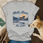 Grey v-neck t-shirt with "Mutts About the Lake" text and graphic of dog jumping into lake.