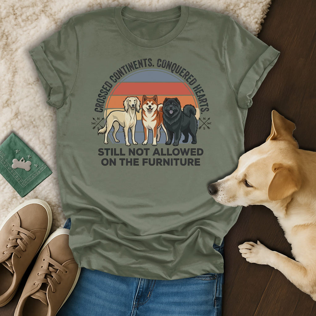 Three dogs stand on a shirt with text about conquered hearts and furniture rules.