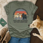Three dogs stand on a shirt with text about conquered hearts and furniture rules.