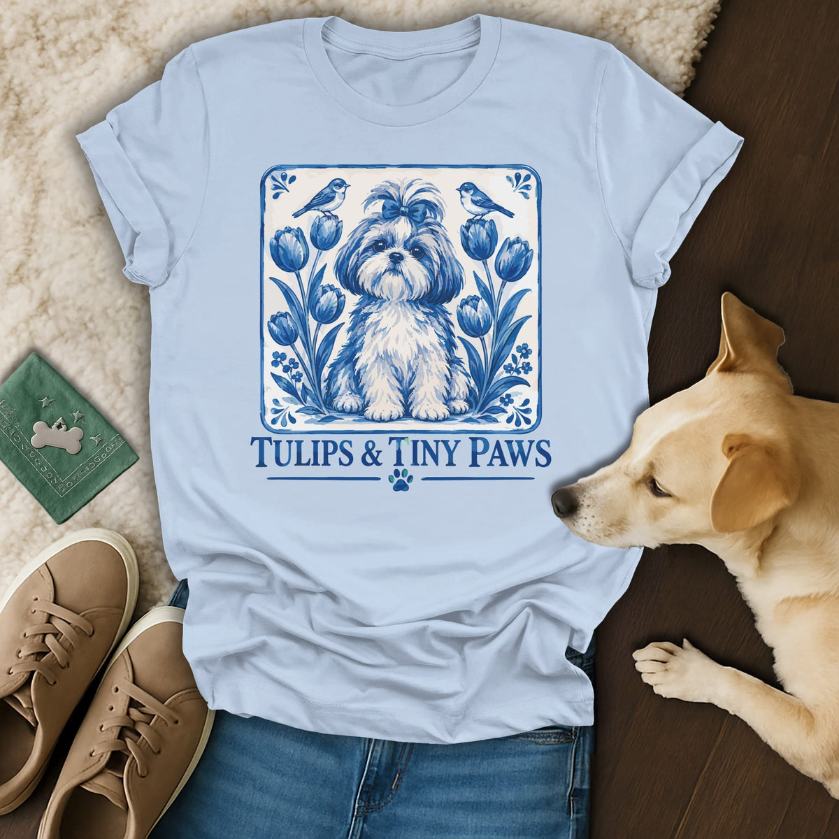 Light blue t-shirt featuring a blue-and-white graphic of a small dog, tulips, and birds with the text Tulips and Tiny Paws.