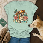 Mint green t-shirt featuring a boxer dog, roses, and the text DOG MOM, laid out with shoes, jeans, and a dog.
