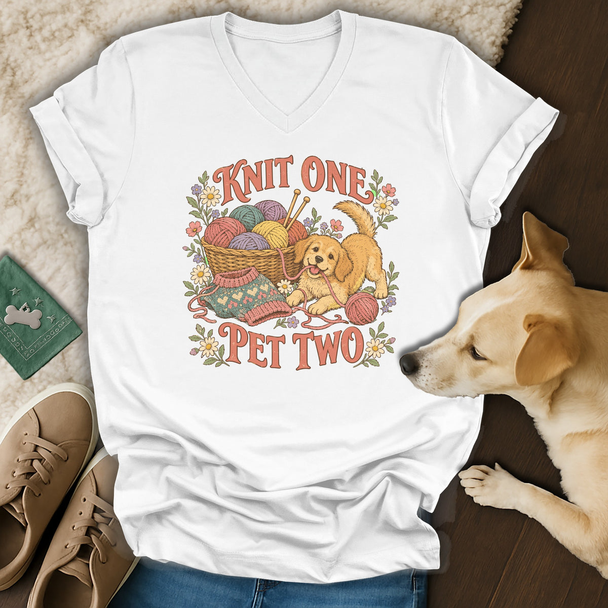 White V-neck t-shirt featuring a cartoon golden retriever playing with yarn and the text Knit One Pet Two.
