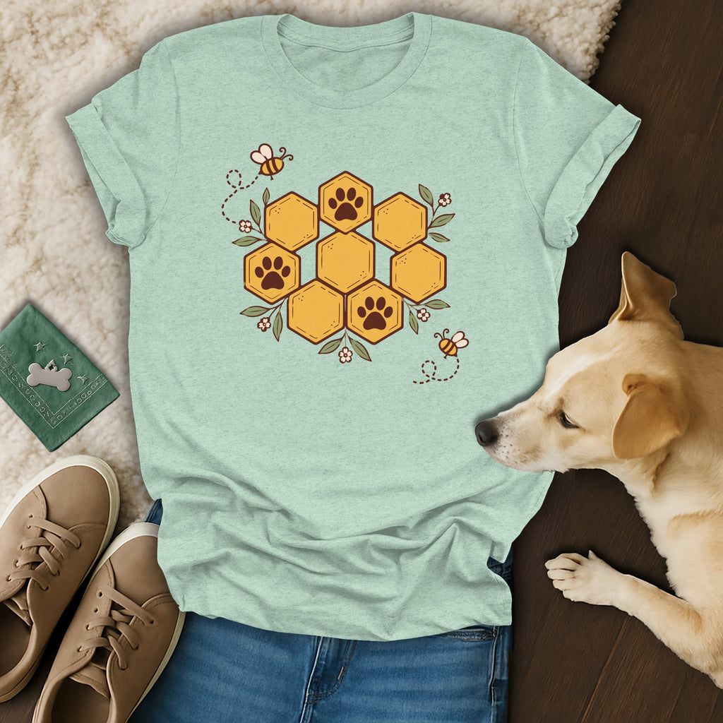 A light green crewneck t-shirt featuring a honeycomb graphic with paw prints and bees, laid out with shoes and a dog.
