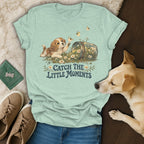 Sage green t-shirt featuring a puppy reaching for bees, with the text Catch the Little Moments.