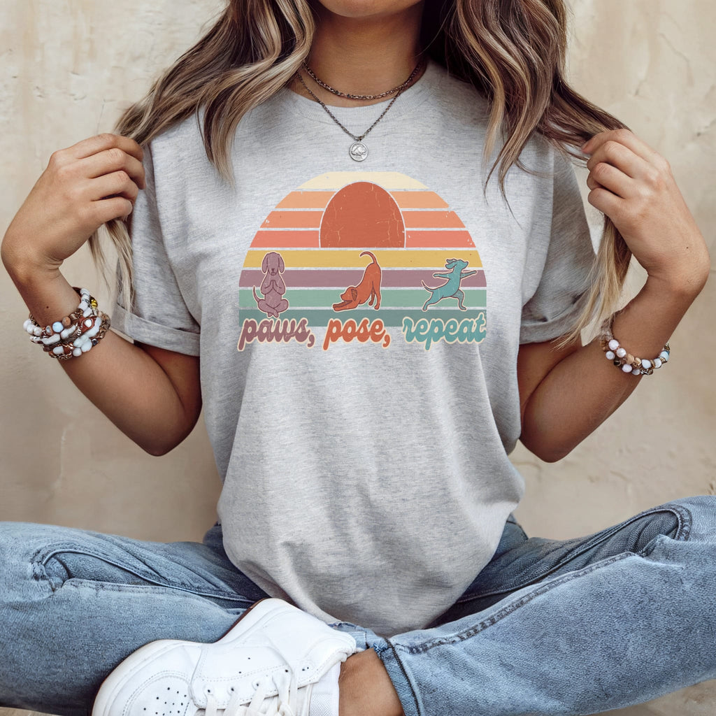 Gray t-shirt with "Paws, Pose, Repeat" yoga dog graphic and sunset.