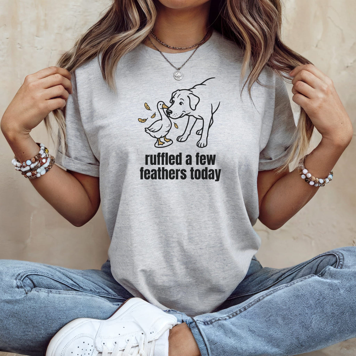 Light grey t-shirt with graphic of a dog and duck, reading "ruffled a few feathers today".