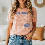 Peach t-shirt with "I'M JUST" and various dog faces.