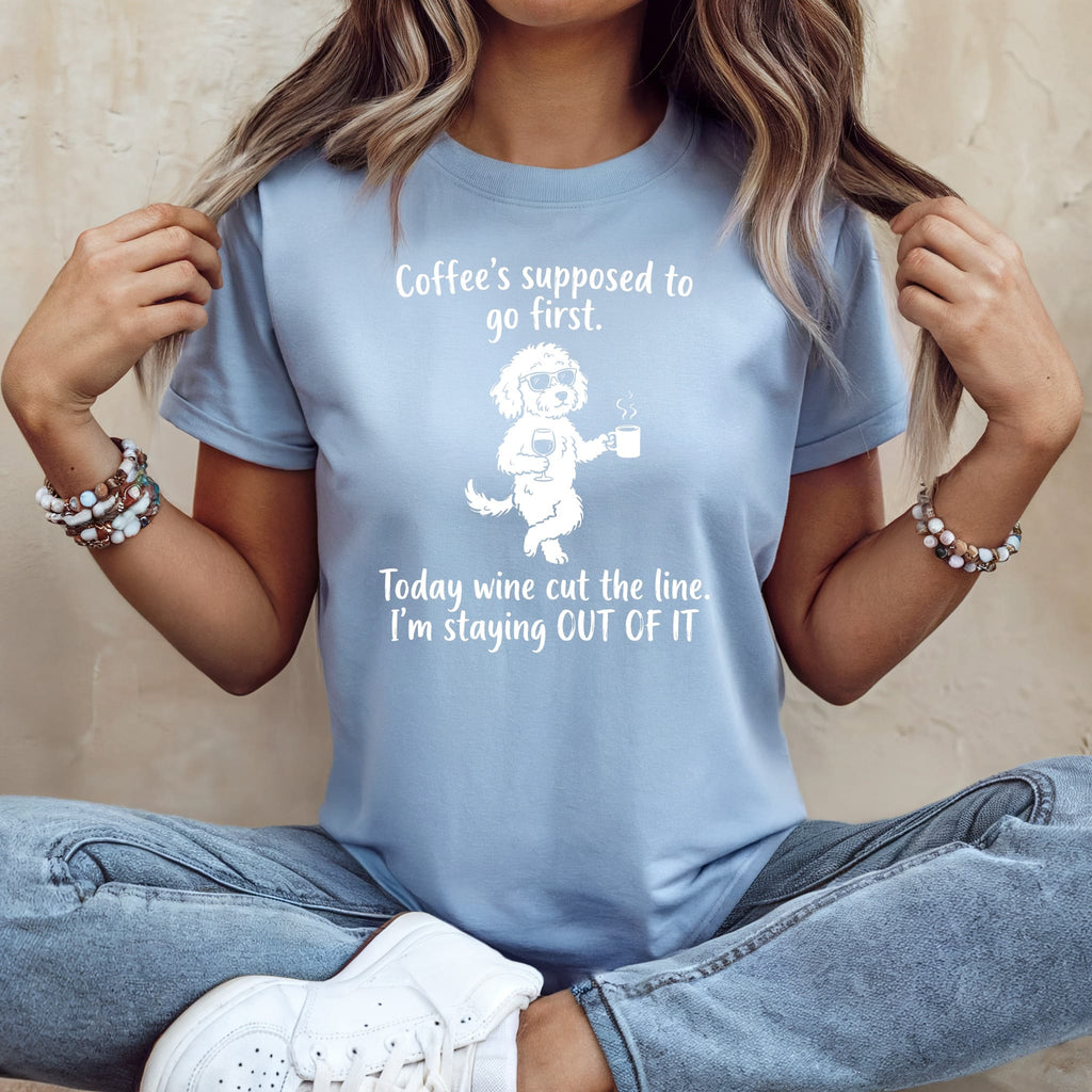Light blue t-shirt with white text and dog graphic: "Coffee's supposed to go first. Today wine cut the line. I'm staying OUT OF IT"