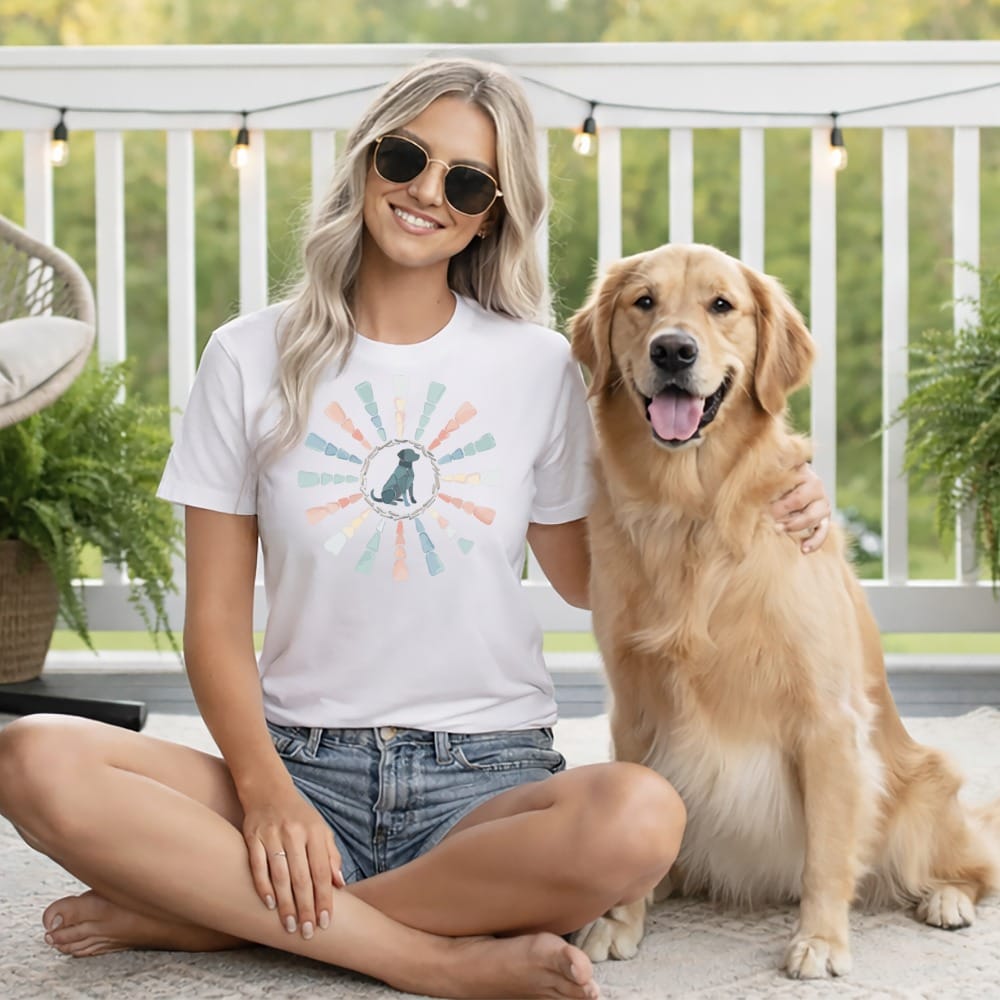 Woman in white t-shirt with a dark dog graphic and golden retriever dog.