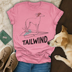 Pink t-shirt with graphic of a dog on a paper airplane, text "TAILWIND".