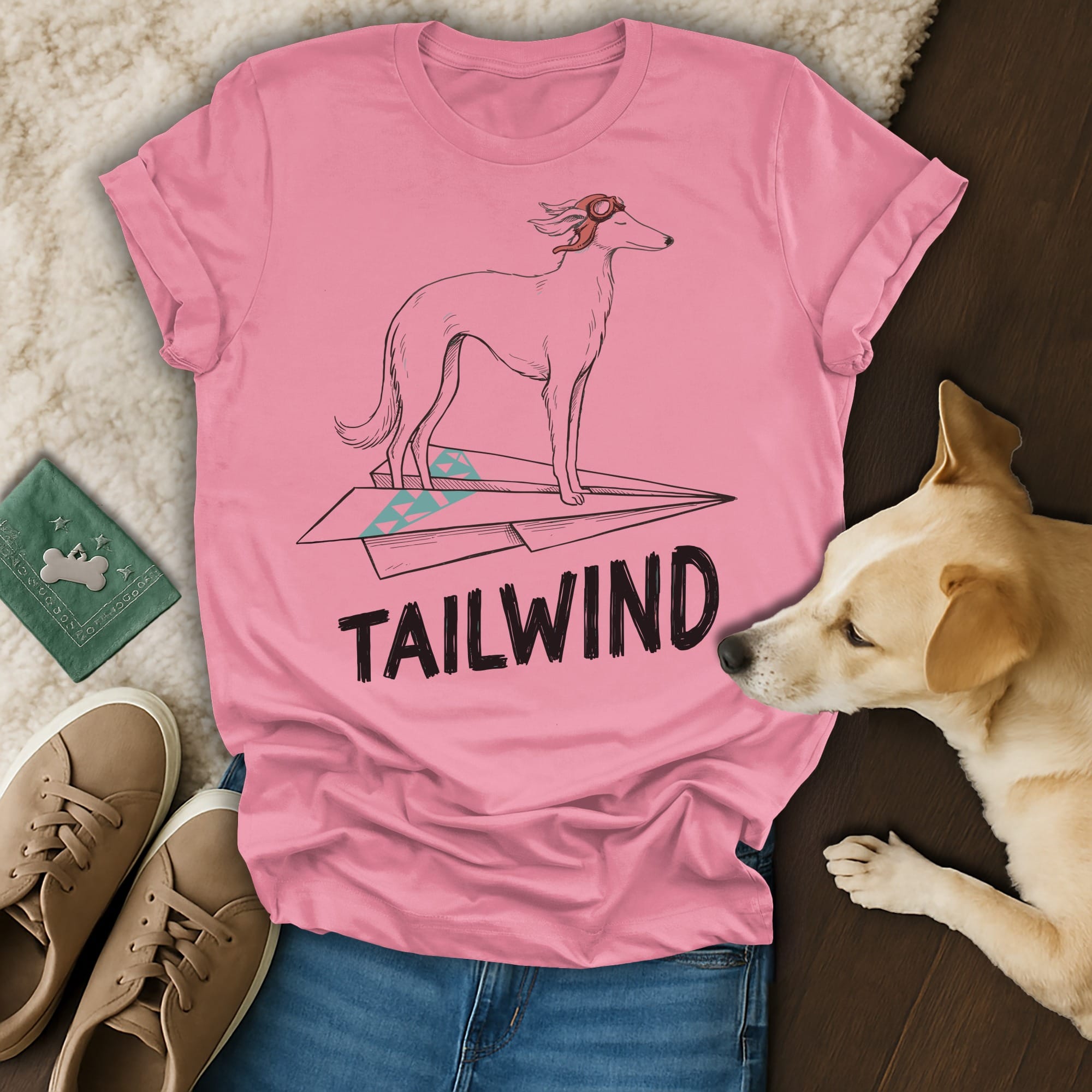 Pink t-shirt with graphic of a dog on a paper airplane, text "TAILWIND".